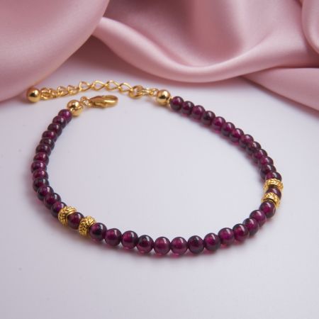 Nahaufnahme eines roten Granat-Armbandes, liegend auf neutralem Untergrund.